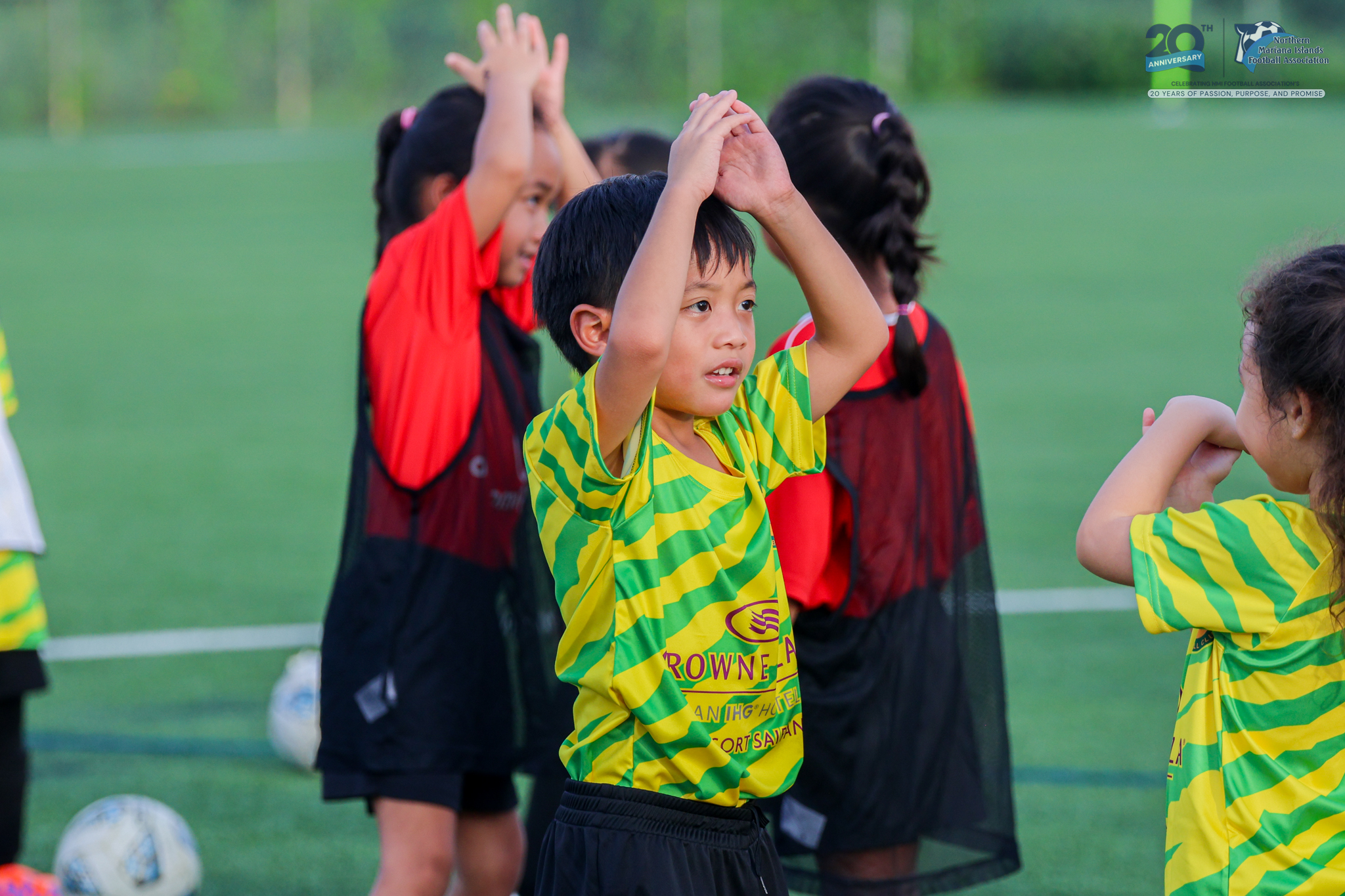 May be an image of 5 people, child, people playing soccer, people playing football, grass and text