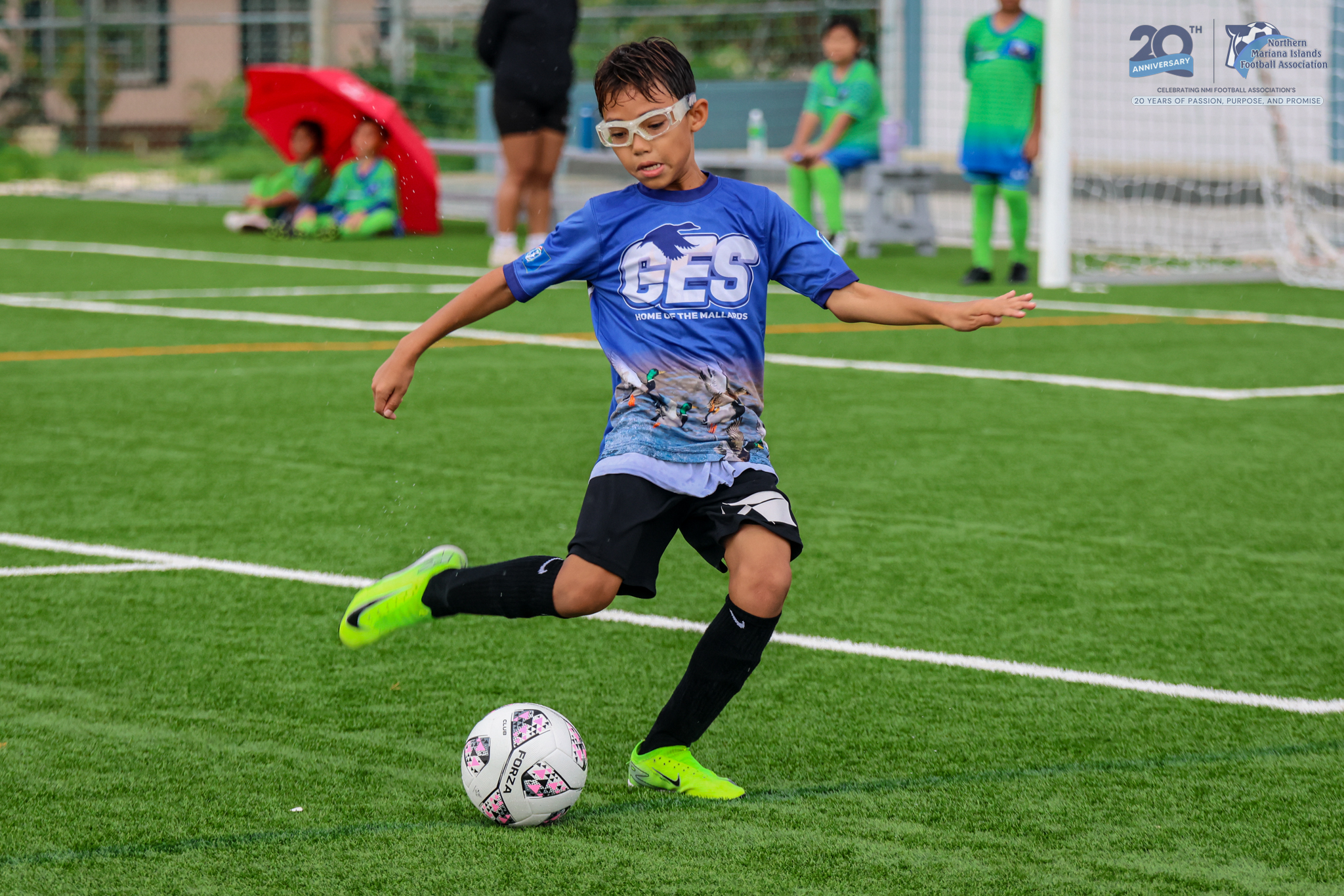 May be an image of 3 people, people playing football, people playing soccer, grass and text