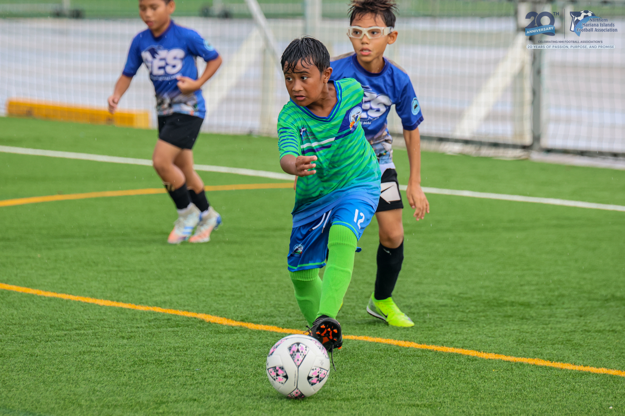 May be an image of 3 people, people playing football, people playing soccer, grass and text