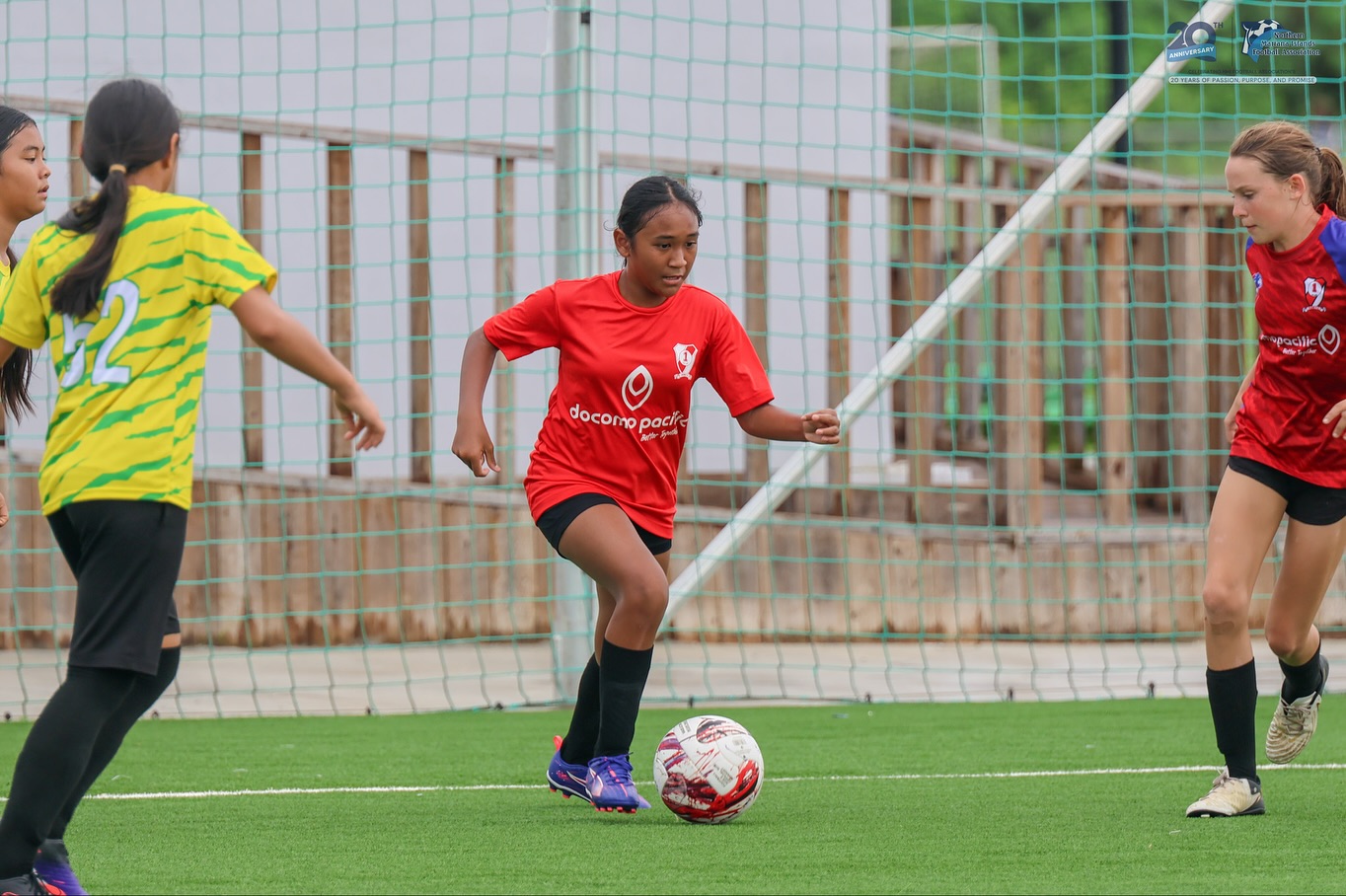 May be an image of 3 people, people playing soccer, people playing football, grass and text